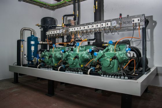 Machine room of a refrigeration system with compressors and refrigerant