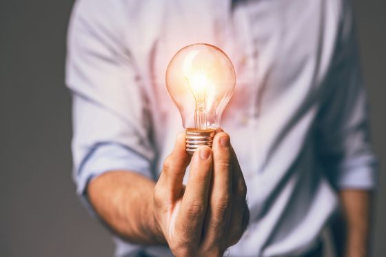 Mann hält eine leuchtende Glühbirne in der Hand