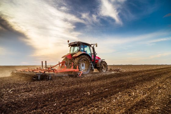 A tractor driving across a field in sunshine