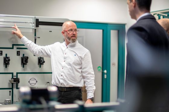 Un homme en chemise blanche explique quelque chose à propos de l’hydraulique.